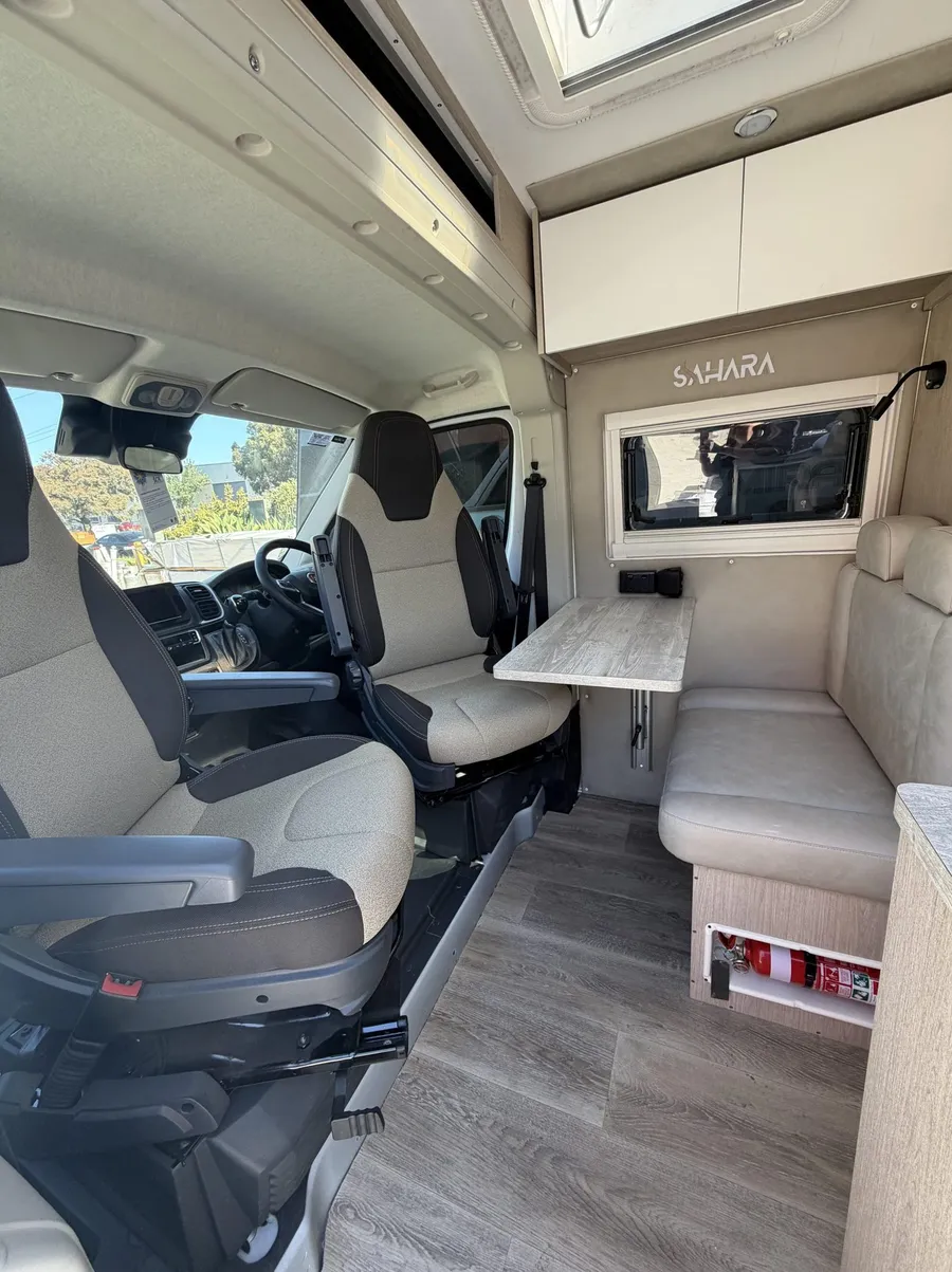Swivel cab seats facing a dining table inside a Sahara custom van